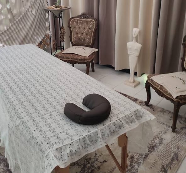A massage table set up on a sunlit terrace with a sea view, towels folded and ready.