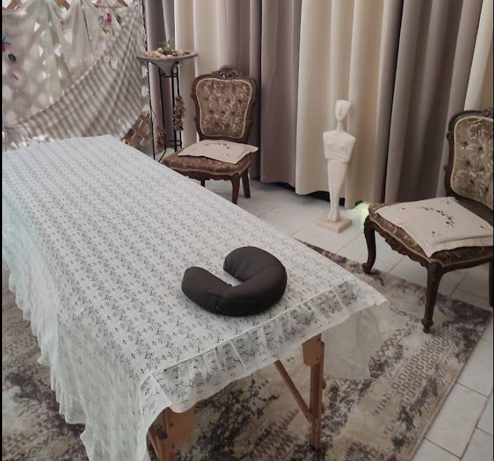 A massage table made up with clean linen in a quiet, bright room, with a folded towel and a small bottle of oil beside it.